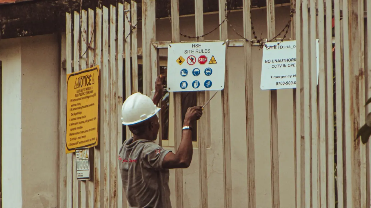 Worker installing occupational safety rules at a worksite entrance
